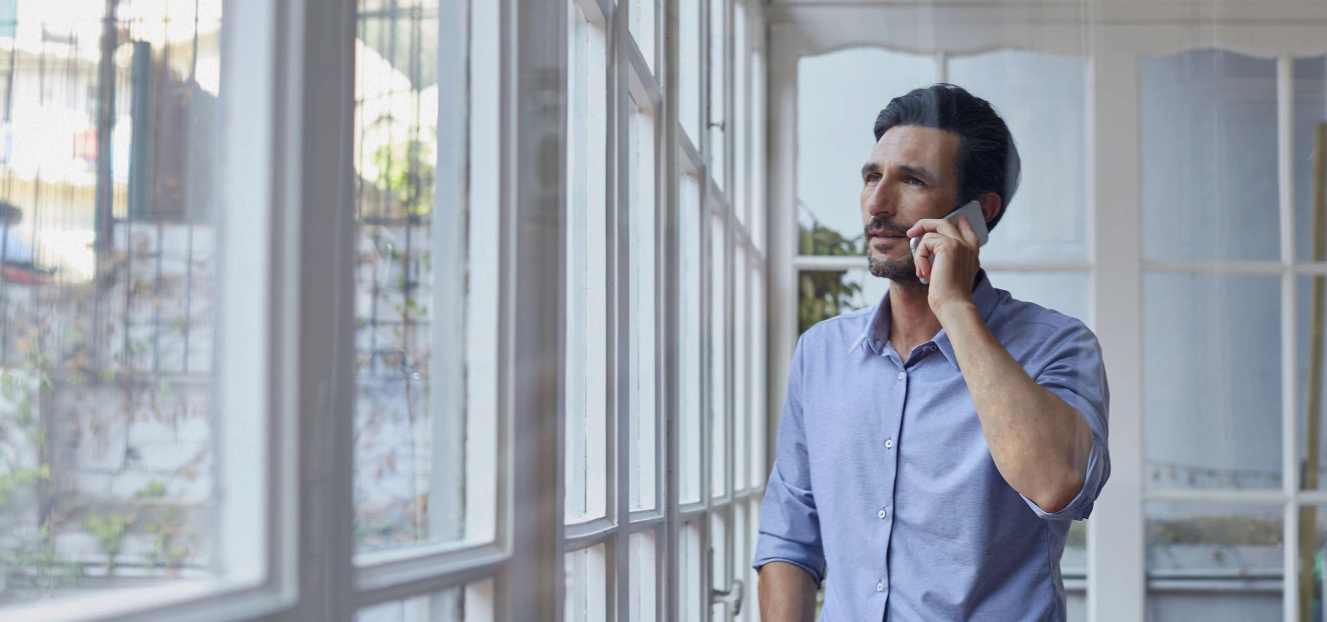 mężczyzna rozmawiający przez telefon przy oknie